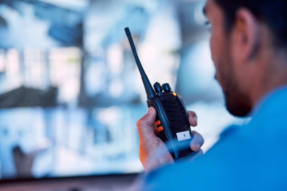 Mitarbeiter des mobilen Sicherheitsdienstes mit Funkgerät vor Überwachungsmonitoren