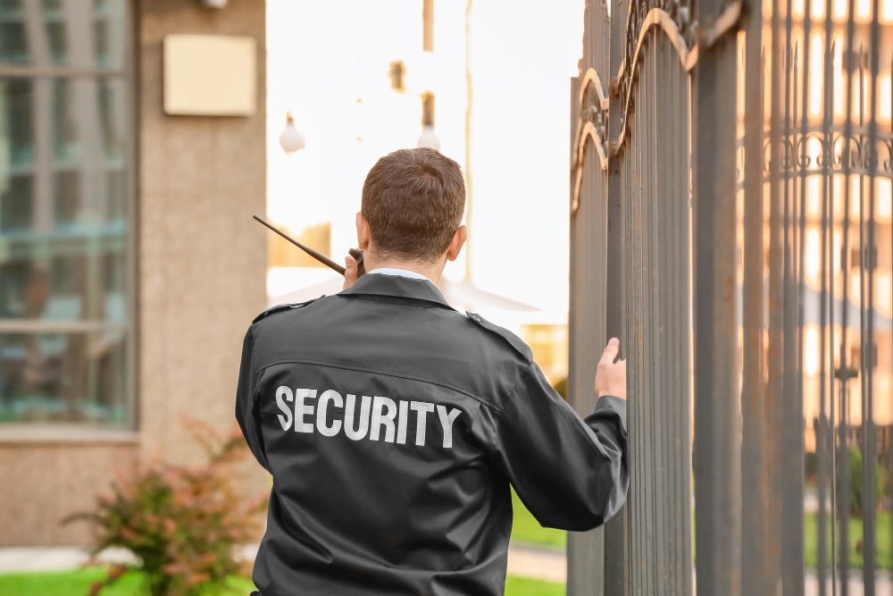 Secure Time Sicherheitsmitarbeiter kontrolliert Eingangstor einer Immobilie mit Funkgerät